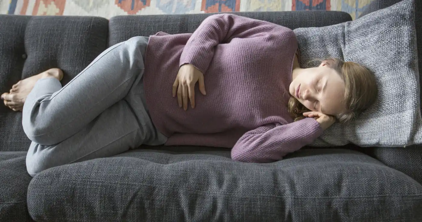 Mujer descansando en el sofá por malestar persistente