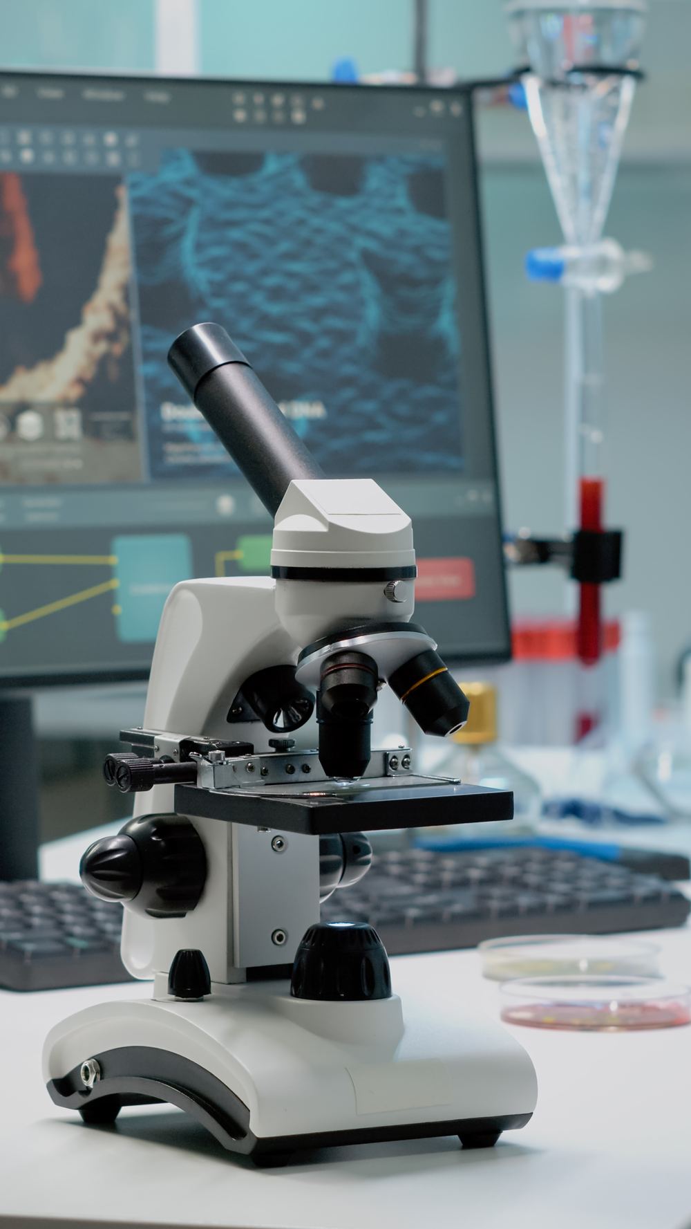 Microscopio de laboratorio junto a una pantalla con visualización de ADN